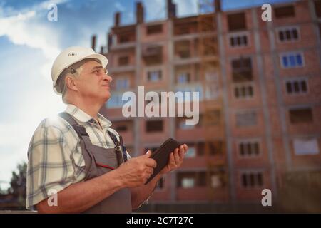 Construction manager controlling building site with pc tablet at sunset Stock Photo