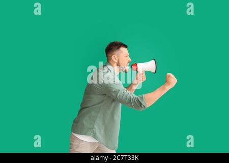 Protesting man with megaphone on color background Stock Photo