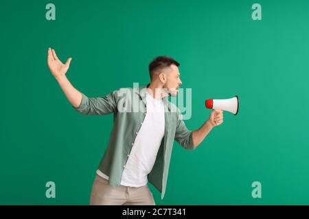 Protesting man with megaphone on color background Stock Photo