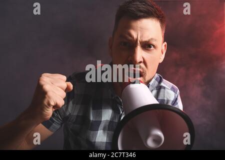 Protesting man with megaphone on dark background Stock Photo