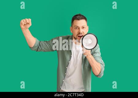 Protesting man with megaphone on color background Stock Photo