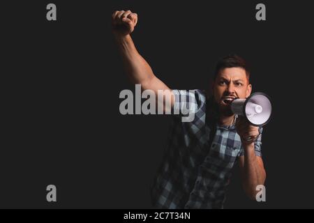 Protesting man with megaphone on dark background Stock Photo