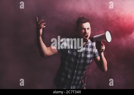 Protesting man with megaphone on dark background Stock Photo