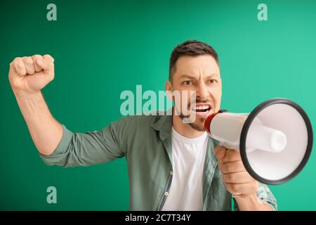 Protesting man with megaphone on color background Stock Photo