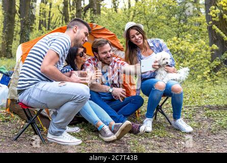 Group of young cheerful friends taking photo selfie while doing a picnic Stock Photo