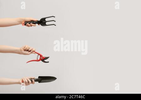 Female hands with gardening tools on light background Stock Photo