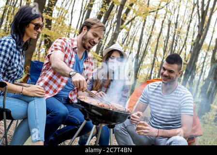 Handsome happy male preparing barbecue outdoors for friends Stock Photo
