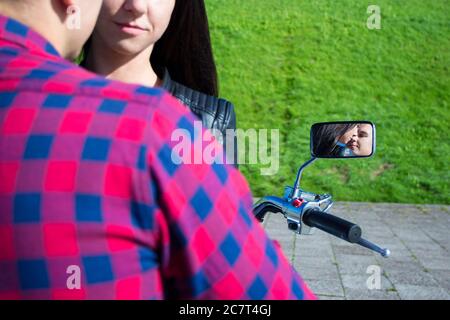 reflection of young kissing couple in motorbike mirror Stock Photo