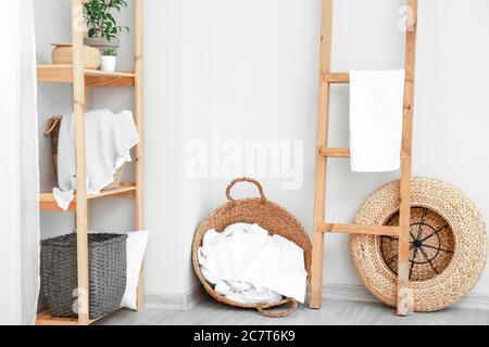 Rack and wicker baskets with towels in room Stock Photo