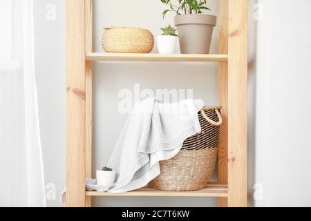 Rack with wicker basket and plaid in room Stock Photo