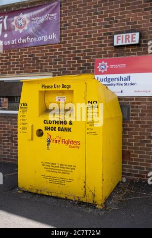 Clothing and shoe recycling bank (yellow metal bin) outside a fire station to raise money for the firefighters charity, UK Stock Photo
