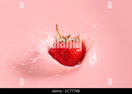 Strawberry falling into a milky pink splash isolated on white ...