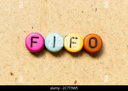 Round color bead with black letter in word FIFO (Abbreviation of first in first out) on wood background Stock Photo