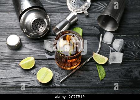 Glass of tasty Cuba Libre cocktail and ingredients on table Stock Photo