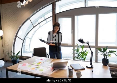 Young ethnic businesswoman busy working with documents in office Stock Photo