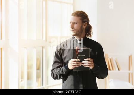 Male priest with Bible at home Stock Photo
