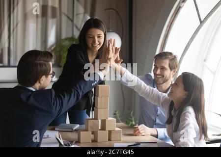 Excited diverse employees give high five at team meeting Stock Photo