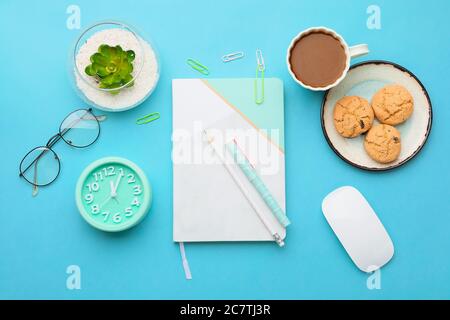 Composition with notebook and cup of coffee on color background Stock Photo