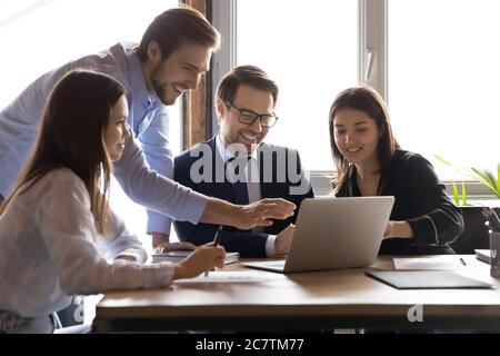 Smiling multiracial colleagues have fun working on laptop Stock Photo