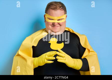 portrait of cunning caucasian superhero man isolated over blue background. fat man is thinking, he conceived something insidious Stock Photo