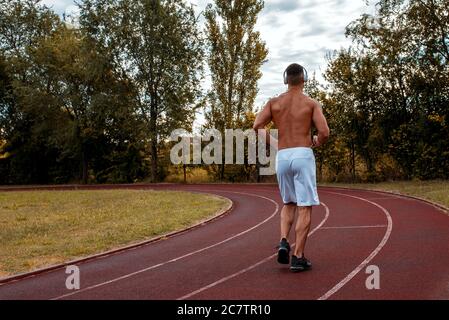 Young Caucasian man wearing headphones and running during his workout Stock Photo