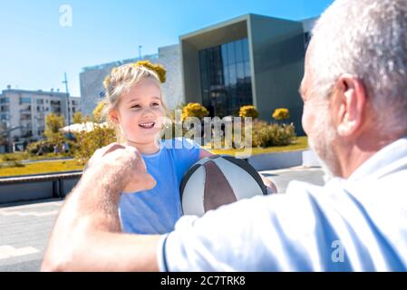 Caucasian grandfather teaching granddaughter to play basketball Stock Photo