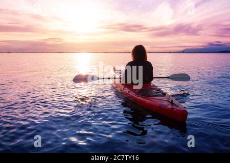 Sea Kayaking in calm waters during a colorful and vibrant sunset. Stock Photo