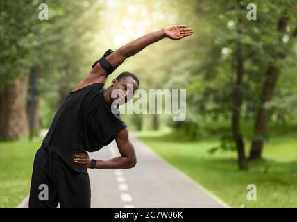 Athletic black guy stretching before training at park Stock Photo