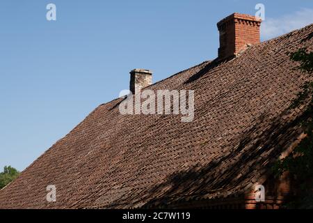 Chimney stacks on tile roof of Ancient style property. Old Brown tile roof. Stock Photo