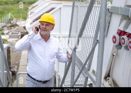 Male construction worker with a yellow helmet talking on the phone Stock Photo