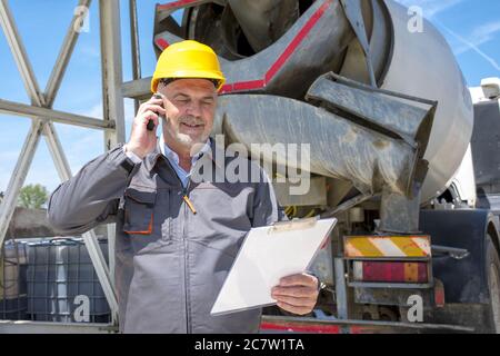 Male construction worker with a yellow helmet talking on the phone Stock Photo