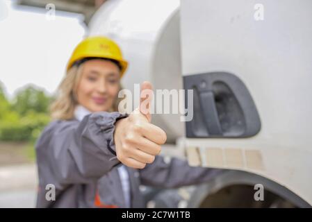 Closeup of a happy female construction worker doing the thumbs-up gesture under the sunlight Stock Photo