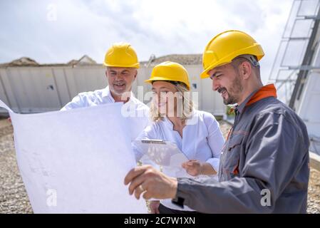 Group of construction workers looking at the plans and documents under the sunlight Stock Photo
