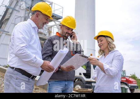 Group of construction workers looking at the plans and documents under the sunlight Stock Photo