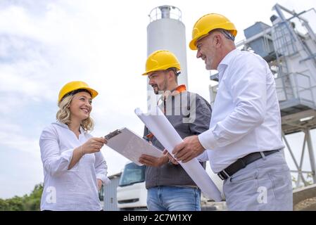 Group of construction workers looking at the plans and documents under the sunlight Stock Photo