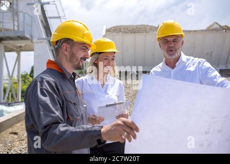 Group of construction workers looking at the plans and documents under the sunlight Stock Photo