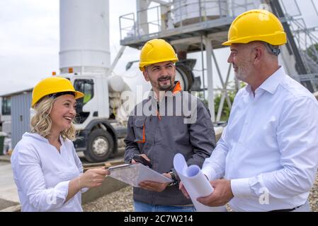 Group of construction workers looking at the plans and documents under the sunlight Stock Photo
