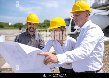 Group of construction workers looking at the plans and documents under the sunlight Stock Photo
