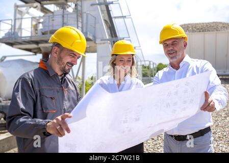 Group of construction workers looking at the plans and documents under the sunlight Stock Photo