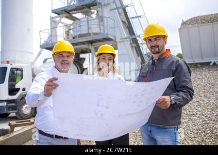 Group of construction workers looking at the plans and documents under the sunlight Stock Photo