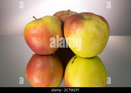 Three red apple on mirroring table. Gorizontal image with copy space. Stock Photo