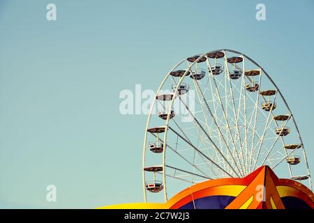 Retro toned picture of a Ferris wheel in an amusement park with cloudless sky, space for text. Stock Photo