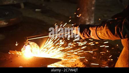 Stationary electric circular cutter instrument cuts metal blank.Professional welder workshop.Sparks flying from metal cutting process. Stock Photo