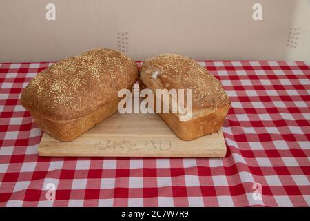 Two loaves of Freshly baked loaf of bread with sesame seeds on a wooden bread board Stock Photo