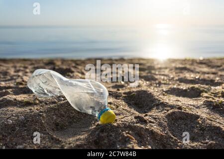 Plastic Bottle Lying On Beach Near Water, Sea Pollution Background Stock Photo