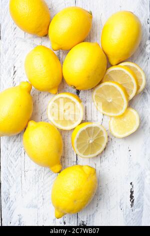 A close group of lemons with some sliced lying on a white board table. Stock Photo