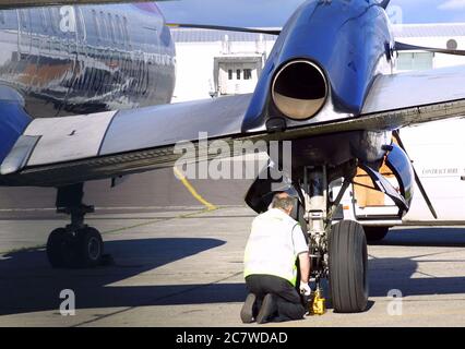 Engineer working on an airplane's landing gear on the tarmac, ensuring safety for flight operations Stock Photo