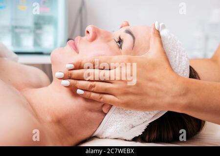 Cosmetologist gives a woman a facial massage, cosmetic procedure. Close up portrait. Side view. Concept of cosmetology and health.