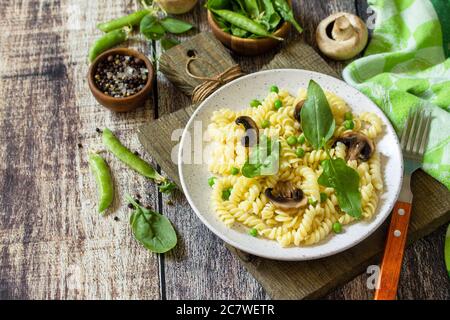 Healthy food. Homemade Pasta fusilli with green peas and grilled champignons on a wooden table.  Copy space. Stock Photo