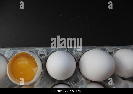 eggs are white chicken in the solution one is broken and the yolk is visible on a gray stone black background there is a place to insert text for the Stock Photo
